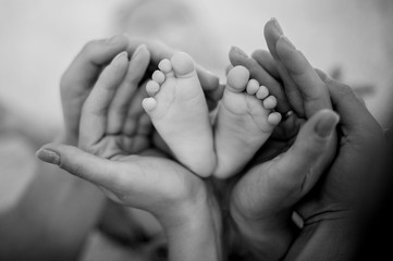 Mother and father holding in their hands daughter feet on the bed