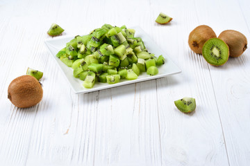 Freshly sliced kiwi fruit with whole kiwis in background.