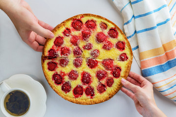 Homemade strawberry pie with coconut chips. Male and female hands take pieces of pie