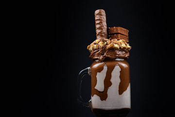 Chocolate extreme milkshake with brownie cake, chocolate paste and sweets. Crazy freakshake food...