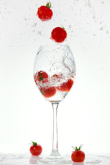 Fresh red tomatoes are jumping from a glass glass