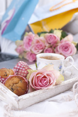 Fototapeta na wymiar a white bed, packages with gifts, fresh coffee, breakfast cakes and a bouquet of pink roses. Good morning Vintage photo. copy space.