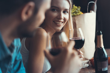 Beautiful young couple is drinking wine and smiling while cooking in kitchen at home.
