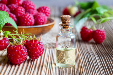 A bottle of raspberry seed oil with fresh raspberries