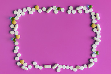 Frame of pills on a pink background. Pills for design. Concept of health, healthy lifestyle. Copy space for advertisement.
