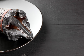 Black ice cream on a black plate with chocolate ice cream in a waffle cone, stylish summer dessert on a blackboard, cold milk product for the designer, creative, copy space