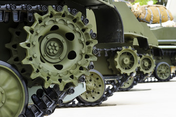 Tank tracks and steel wheels of heavy armored vehicles with green bodywork in row, military industry, modern army equipment, selective focus  - 210742288