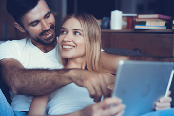 Happy couple in love surfing on tablet at home.