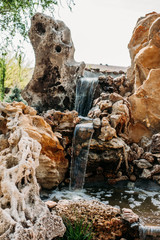 Decorative waterfall in the Park with stones. A cozy place with an artificial waterfall in the Park.