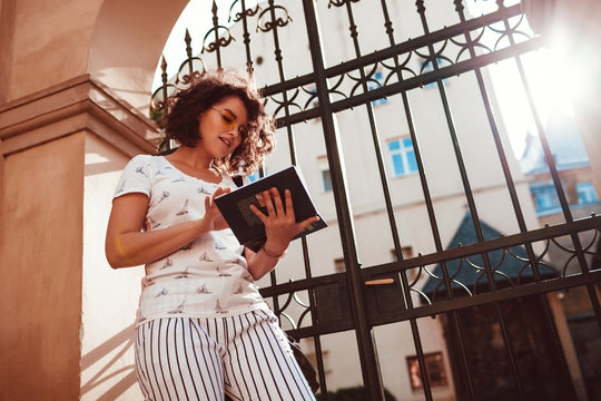 Beautiful college girl reading a book outdoors. Teenager student learning in the yard of university