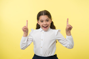Little genius has an idea. Happy girl keep fingers raised on yellow background. Back to school....
