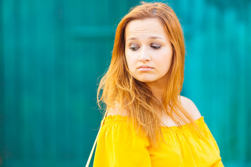 The girl looks to the side and lowered her eyes against the background of the wall