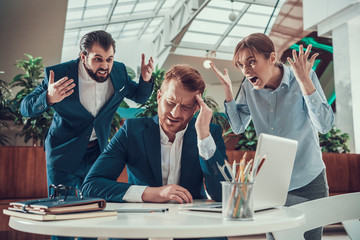 People shout at distressed worker in office.