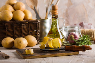 Peeling potatoes on dark cutting board on kitchen background