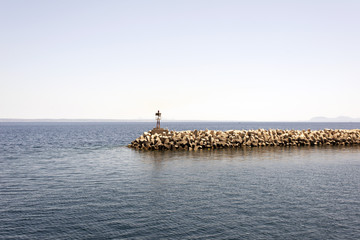 Fototapeta na wymiar A view of a pier made of stones in Greece in summer