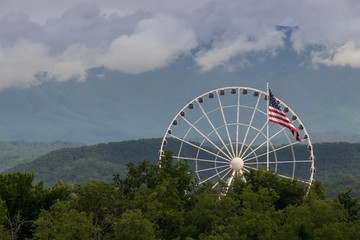 American flag with ferris wheel and mountains in background