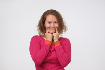 European woman pretending to be happy. She is pinching edges of her mouth up.