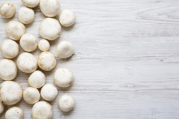 Champignon mushrooms on a white wooden table, top view. From above. Copy space.
