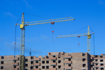 tower crane against the blue sky, the process of building a multi-storey building