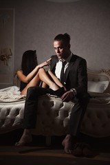 The guy and the girl on the bed.A girl and a guy in a beautiful interior.Girl posing next to a guy in a suit.I threw my legs in bed on my boyfriend.Girl with beautiful feet in heels in bed with a guy.