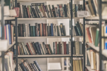 Blurred bookshelves of bookcase with books in public library. Blur effect. Vintage retro background. Concept of learning, school, back to school, education