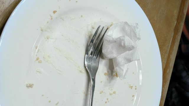 Person finished to eat and put fork knife and napkin serviette on the empty plate. Cafe restaurant casual scene. Vertical format video.