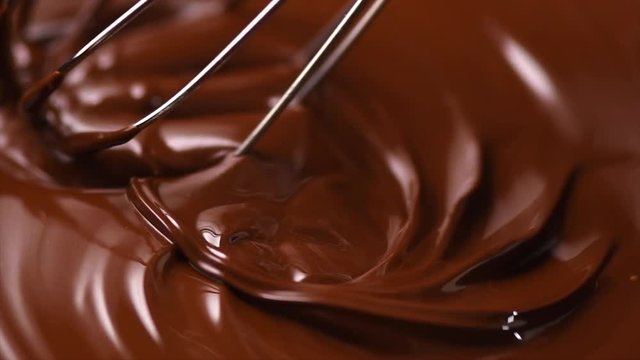 Chocolate. Mixing melted dark chocolate with a whisk. Closeup of liquid hot chocolate swirl. Confectionery. Slow motion 4K UHD video 3840X2160