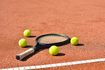 Close up view of tennis racket and balls on the clay tennis court