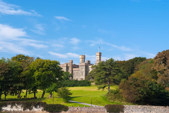 Lews Castle on estate landscape in Stornoway, United Kingdom. Castle with green grounds on blue sky. Victorian style architecture and design. Landmark and attraction. Summer vacation and wanderlust