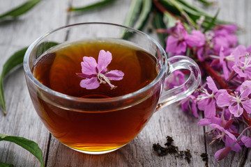 Traditional Russian herbal drink Ivan-tea in a transparent cup close-up on a wooden table. Positively affects the human body