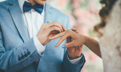 Bridegroom put an engagement ring on bride.