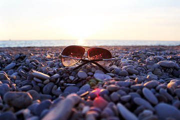 Sunglasses lie on a stone beach on the seashore