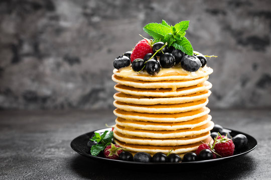 Pancakes with fresh berries. Pancakes with raspberry, blueberry, black currant and honey