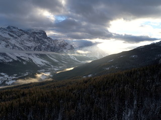 Fototapeta premium drone flying above pine tree forest on cold winter morning with sunset and alps mountain range in background