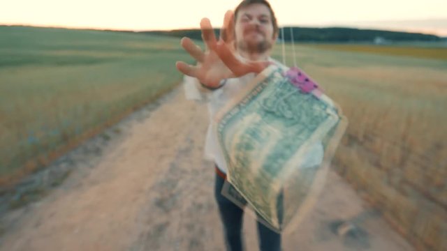 a young businessman runs for a banknote which is suspended on a rope