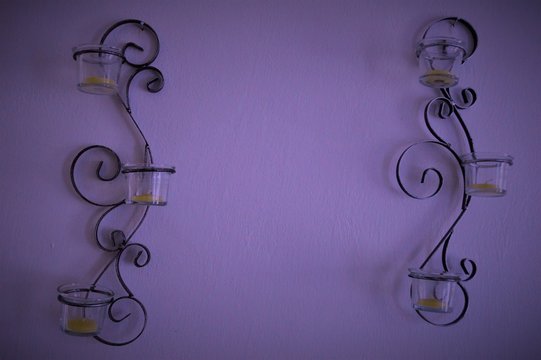Decora&ccedil;ao de parede feita de ferro com copos de vidro e velas.