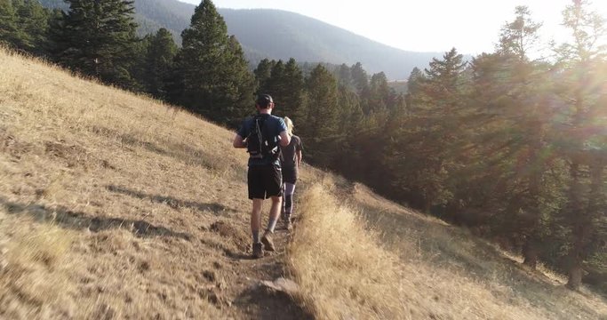 Couple hikes on mountain trail in Montana, aerial