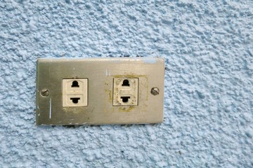 The old plug on blue wall. Selective focus. Industrial, Technology and interior concept.