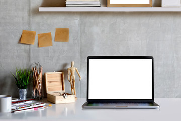 Loft workspace with mockup laptop computer and artist supplies on wooden desk.