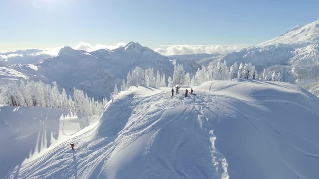 Pan left aerial, skiers on mountain ridge in Washington
