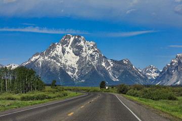 Fototapeta premium Traveling down the road toward the Grand Teton mountains in Jackson Hole, Wyoming.