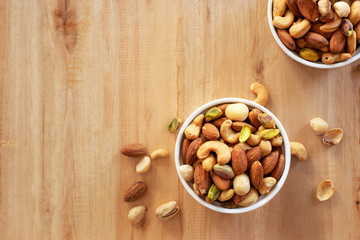 mixed nuts in white ceramic bowl on wooden background
