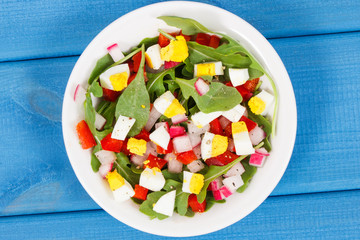 Fresh prepared salad in glass bowl on blue boards, healthy nutrition concept