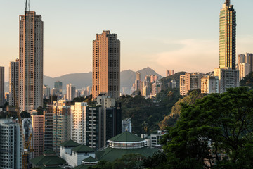Sunset over tall apartment tower in Happy Valley in Hong Kong island with the peaks of kowloon in the back in Hong Kong, China