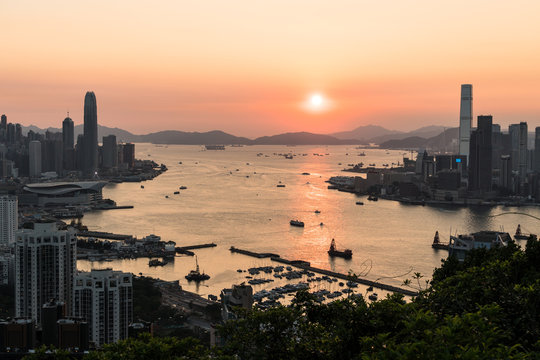 Stunning view of the sunset above the Victoria harbor in Hong Kong with the skyscraper of Hong Kong island in the left and Kowloon on the right