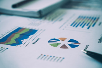 Many charts and graphs with pen. Concept image of data gathering and statistical working.