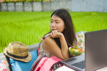 young beautiful and happy Asian digital nomad or Chinese tourist woman  networking outdoors with...
