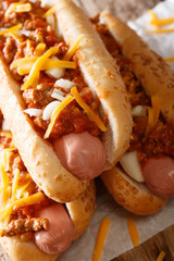 Chili hot dog with cheddar cheese and spicy sauce close-up. vertical