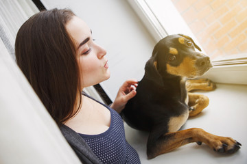 Cute young girl and inbred dog sits and looks out the window.