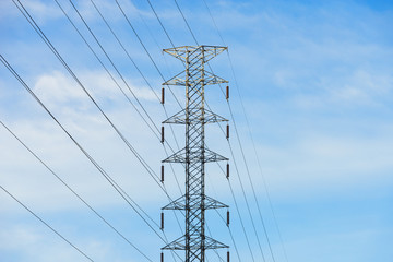 High voltage transmission tower, upper part. .Power electric line on pylon  with cloud blue sky background, low angle view..